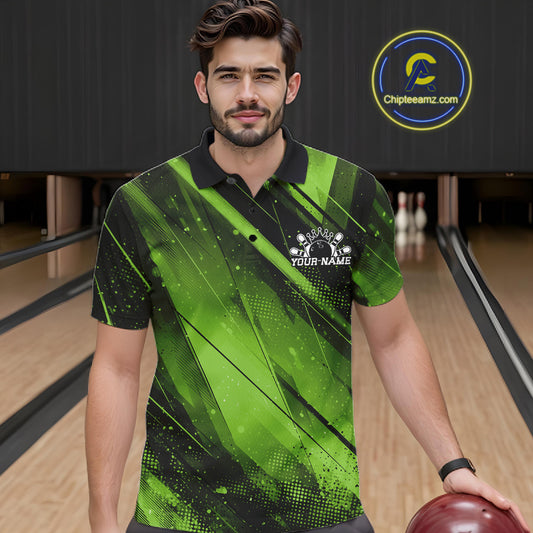 Man wearing a green and black bowling shirt with a logo in a bowling alley.