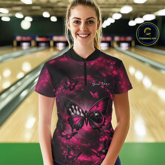 Female model at a bowling lane wearing a quarter-zip bowling shirt with a pink and black butterfly artwork incorporating a bowling ball body.