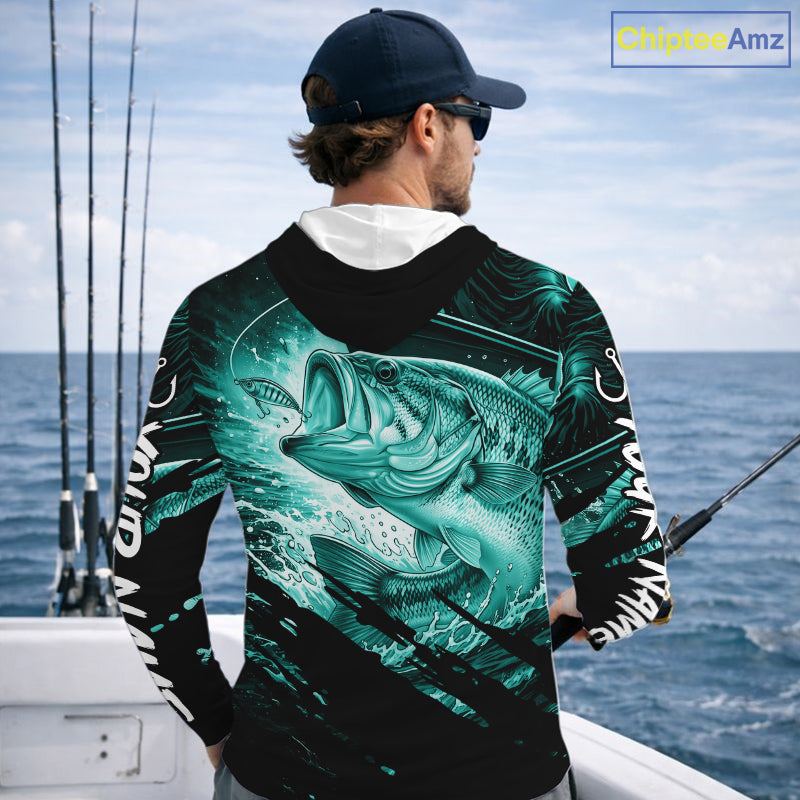 Person wearing a teal and black bass fishing shirt with a fish design, standing by the ocean.