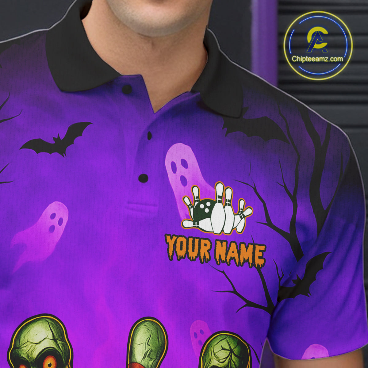 A close-up of a person wearing a purple Halloween-themed polo shirt with a black collar. The shirt features a spooky print with black bats, white ghosts, green zombie heads, and a bowling pin graphic with the text 'YOUR NAME'.