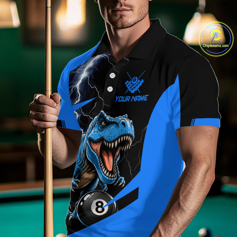 A man in a pool hall wearing a custom blue and black polo shirt with a graphic of a roaring T-Rex dinosaur, lightning, and a billiard 8-ball. He is holding a pool cue.