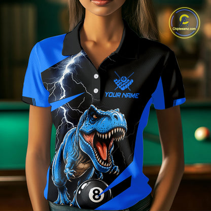 A woman wearing a custom-designed polo shirt with a blue and black background, featuring a graphic of a roaring blue T-rex, lightning bolts, a billiard 8-ball, and placeholder text 'YOUR NAME' and a shooting gallery design. The background is a blurred pool hall with a green pool table.