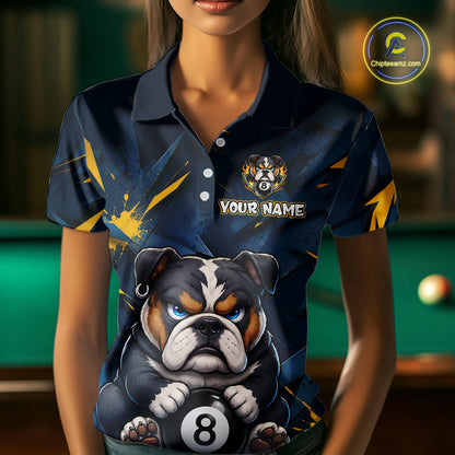 A front view of a custom blue and yellow billiards polo shirt worn by a female model . The shirt features  a cartoon bulldog with its paw on an 8-ball on the front. A 'YOUR NAME' text placeholder . The background is a blurred billiards room with a green pool table.