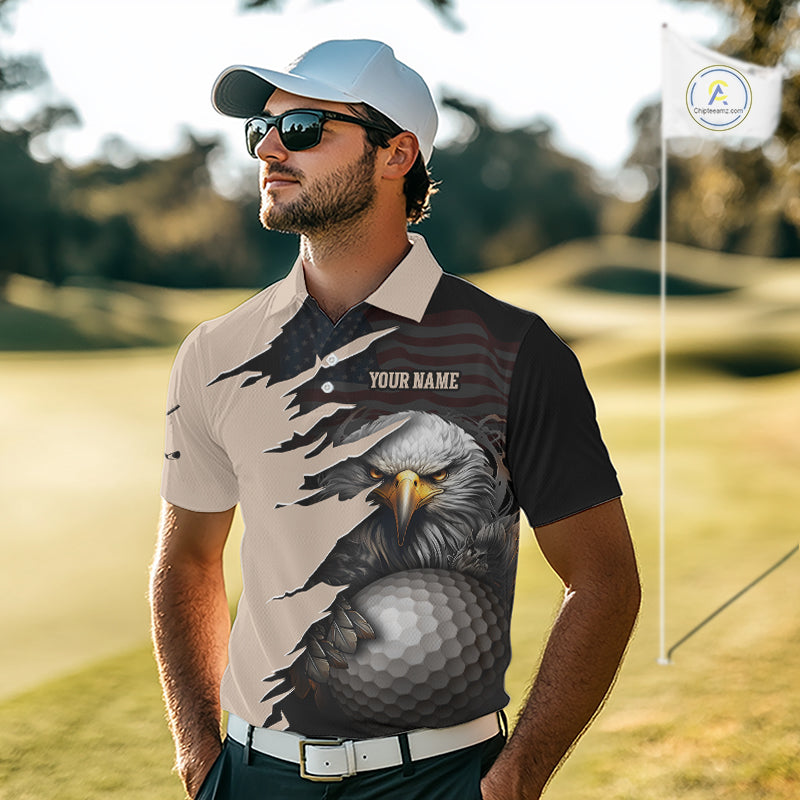 A man wearing a custom golf polo shirt with a bald eagle and golf ball graphic, standing on a golf course. The shirt features a split design with a beige left side and a black right side, with a torn-paper effect revealing a US flag pattern underneath.