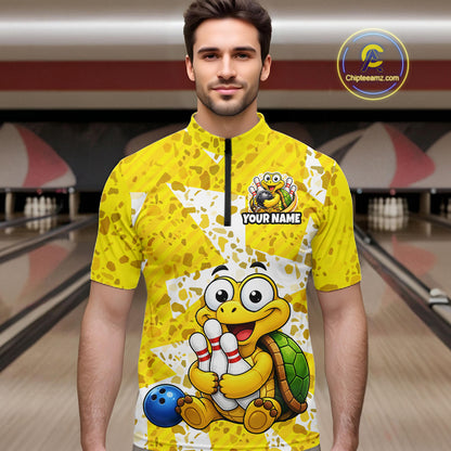 Man wearing a yellow bowling jersey with cartoon turtle design in a bowling alley.