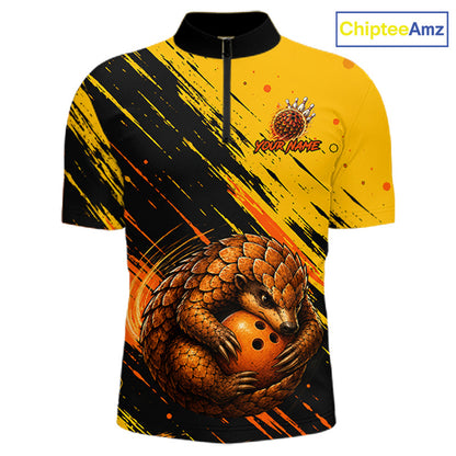 A short-sleeve quarter-zip athletic shirt with a bold yellow and black brushstroke design, featuring a large pangolin graphic wrapping around an orange bowling ball on the front. The shirt has a black collar and zipper, with a customizable 'YOUR NAME' placeholder logo on the chest.