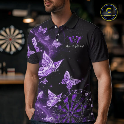 A man wearing a black short-sleeve polo shirt with a purple and lavender butterfly and dartboard graphic design, featuring a customizable name print on the chest. The background is a blurred indoor setting with a dartboard.