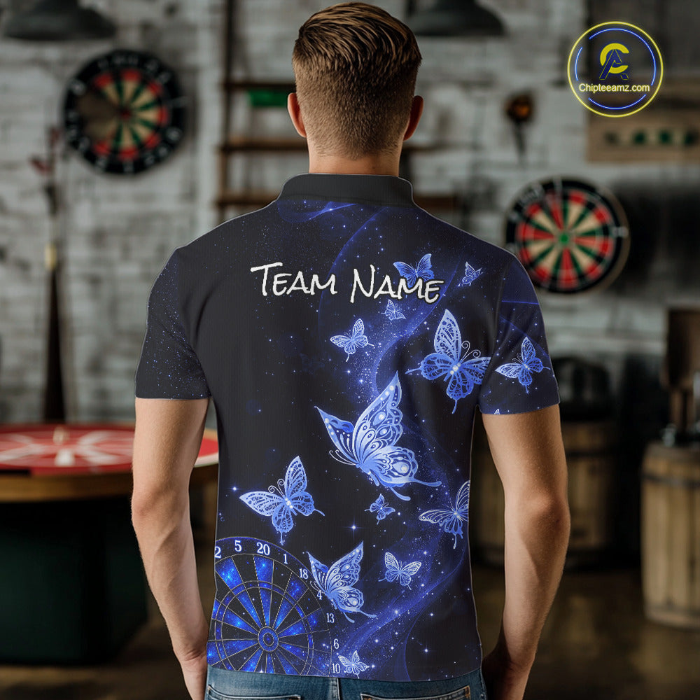 A man viewed from behind wearing a short-sleeve polo shirt with a blue and black butterfly and starry space print, featuring the text 'TEAM NAME' on the back. The background shows a blurred indoor room with dartboards.