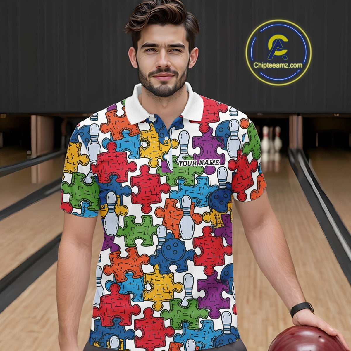 A man wearing a colorful short-sleeve polo shirt with a jigsaw puzzle pattern in red, blue, green, yellow, orange, and purple, standing in a bowling alley holding a bowling ball.