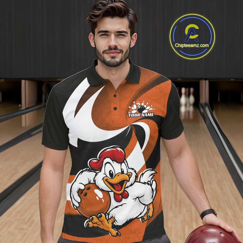 A man wearing a custom bowling shirt with a cartoon chicken graphic, standing in a bowling alley holding a bowling ball. The shirt features a black and orange design with a white swoosh and a custom name patch on the chest.