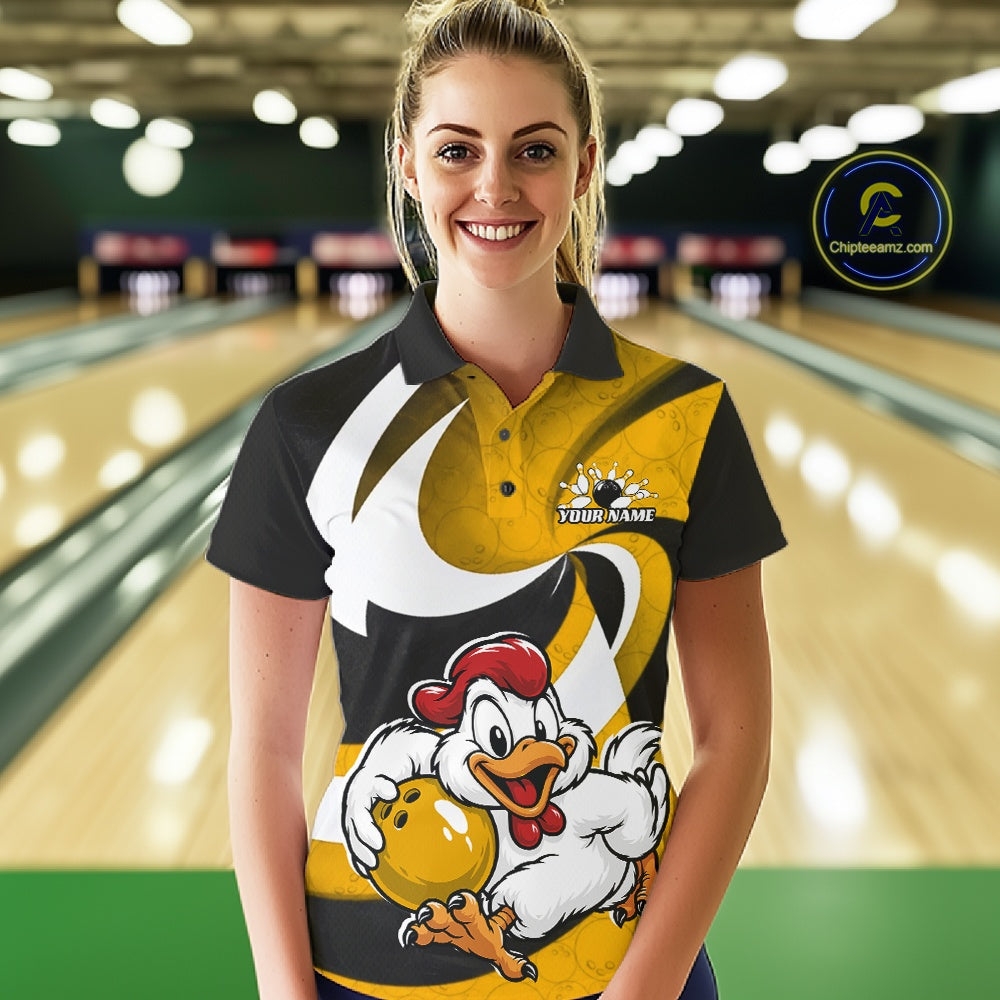 A woman standing in a bowling alley wearing a custom printed bowling shirt with a cartoon rooster graphic and the text 'YOUR NAME'. The shirt features a black, yellow, and white design.