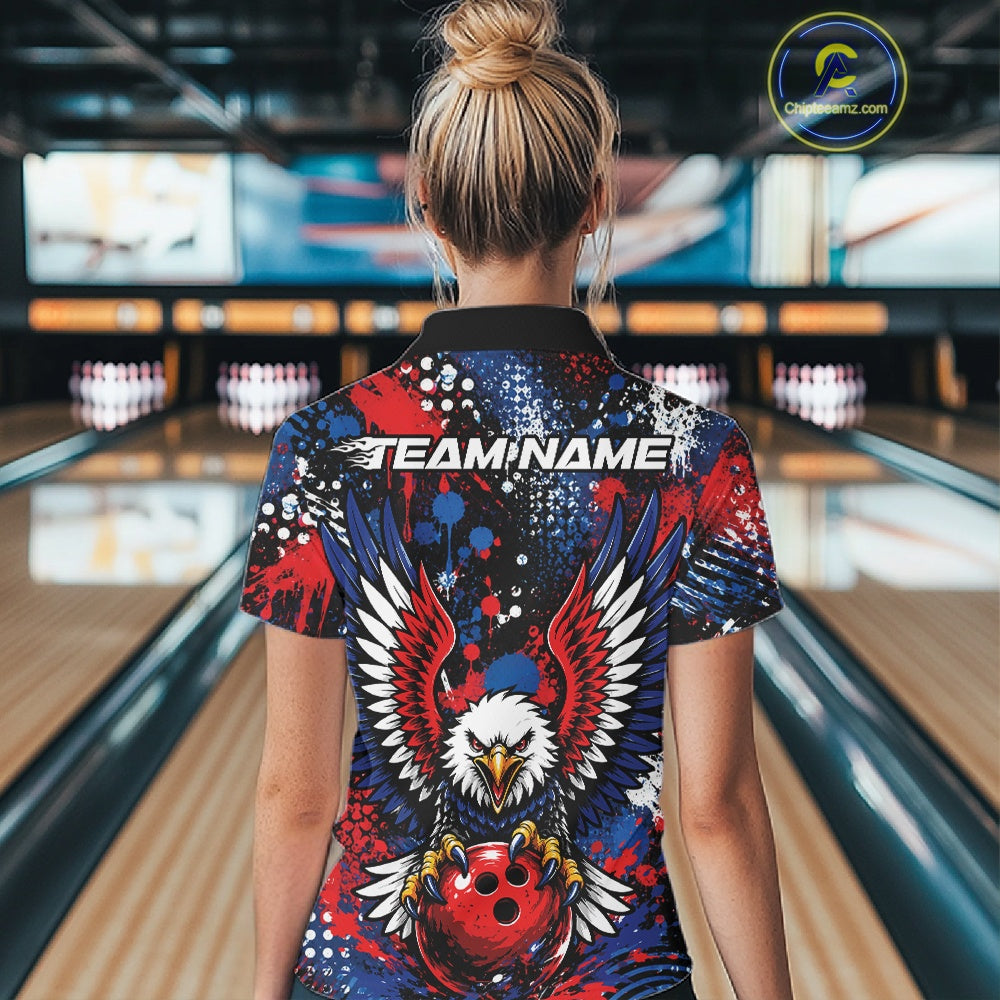 Back view of a woman in a bowling alley wearing a custom team jersey with red, blue, white, and black splatter graphics, â€œTEAM NAMEâ€ text, and a large eagle clutching a red bowling ball.