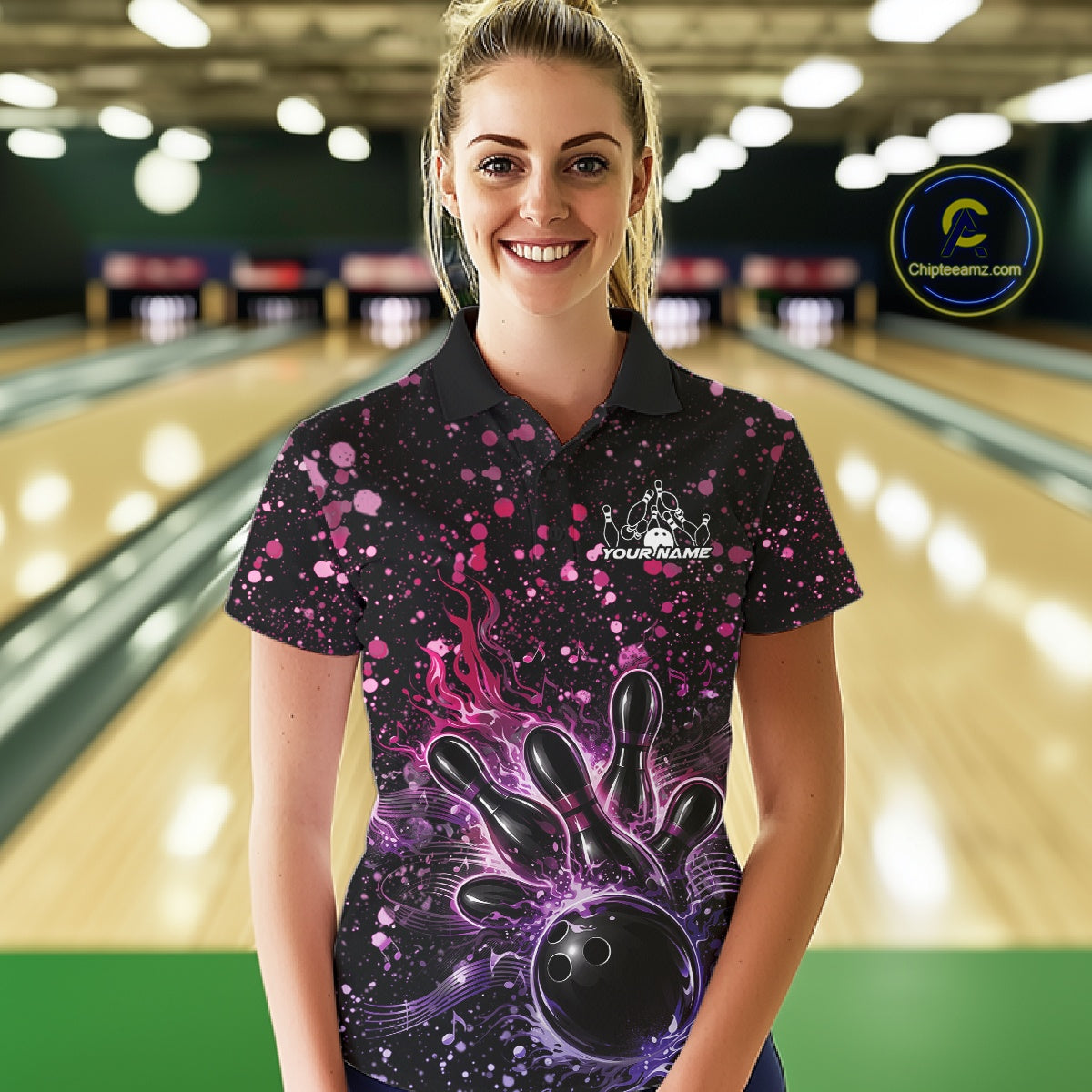 Female model wearing a black bowling polo shirt at the bowling lane with fiery bowling artwork and pink-purple paint splatter details.