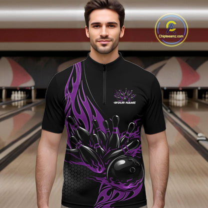 Male model front view in a bowling lane wearing a black quarter zip shirt featuring purple flaming black bowling ball striking pins in a dynamic sports action design.