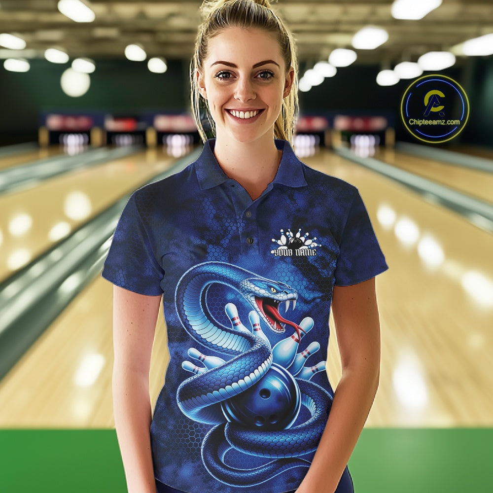Female model wearing a bowling polo at the bowling lane with blue cobra artwork and scattered bowling pins.