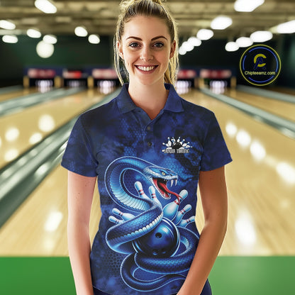Female model wearing a bowling polo at the bowling lane with blue cobra artwork and scattered bowling pins.