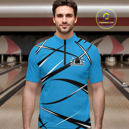Front view of a male bowler wearing a blue, black, and white bowling quarter zip shirt in a bowling alley