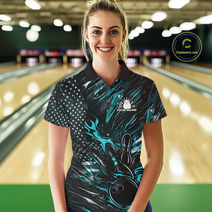 Female model at a bowling lane wearing a black and turquoise blue bowling polo shirt with patriotic bowling strike artwork and vibrant graphics.