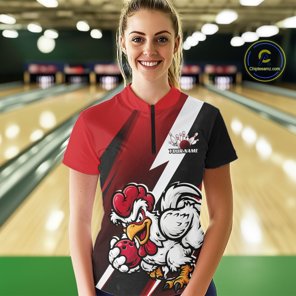 A woman standing in a bowling alley wearing a short-sleeve bowling jersey with a red, black, and white design, featuring a cartoon rooster mascot holding a bowling ball and the text 'Your Name' on the front. 