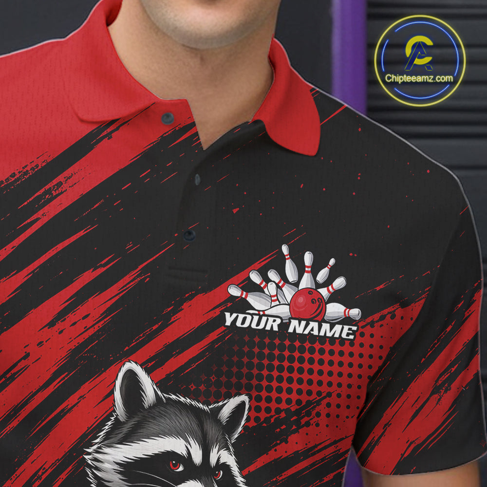 A close-up of a person wearing a short-sleeve polo shirt with a black and red graphic design, a raccoon illustration, and a bowling pin/ball graphic above the text 'YOUR NAME'. 