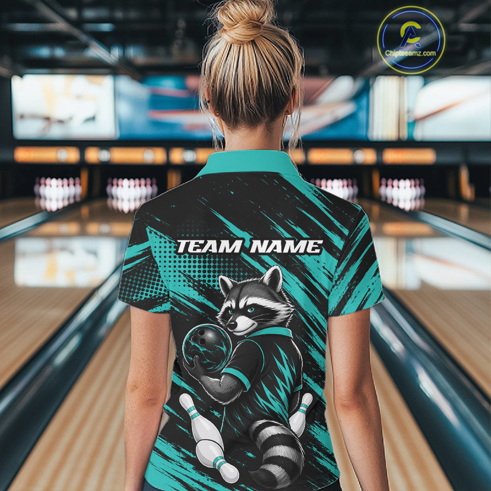 A woman viewed from behind wearing a short-sleeve bowling polo shirt with a raccoon graphic and 'TEAM NAME' text, standing in a bowling alley. The shirt has a black and teal design with a raccoon illustration holding a bowling ball.
