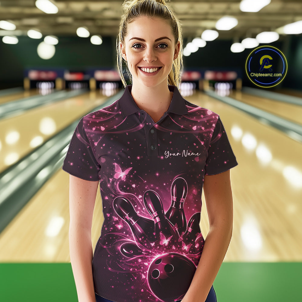 Female model in a black and pink bowling polo shirt at the bowling lane with luminous butterfly bowling graphics.