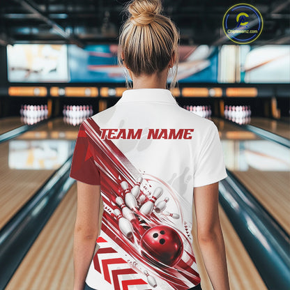 A woman viewed from behind wearing a white short-sleeve bowling-themed polo shirt with a red and white graphic design on the back, standing in a bowling alley.