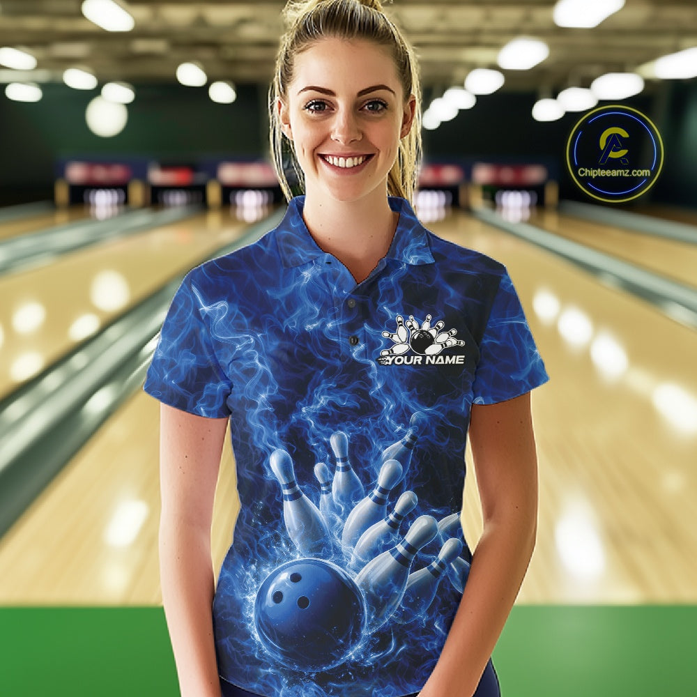 Female model in a bowling alley wearing a polo with blue bowling ball artwork and fiery bowling graphics.