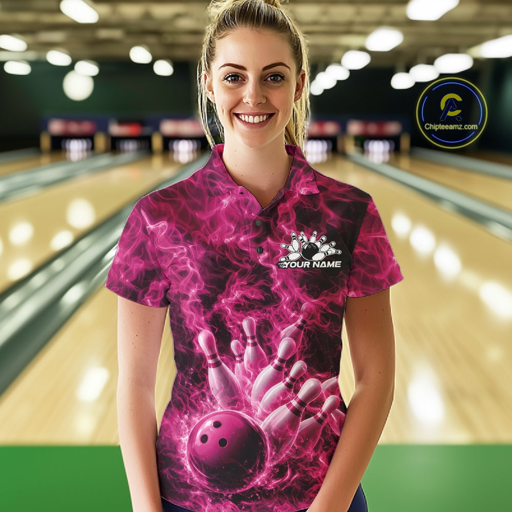 Female model in a bowling lane wearing a polo with pink bowling ball strike artwork and fiery graphics.