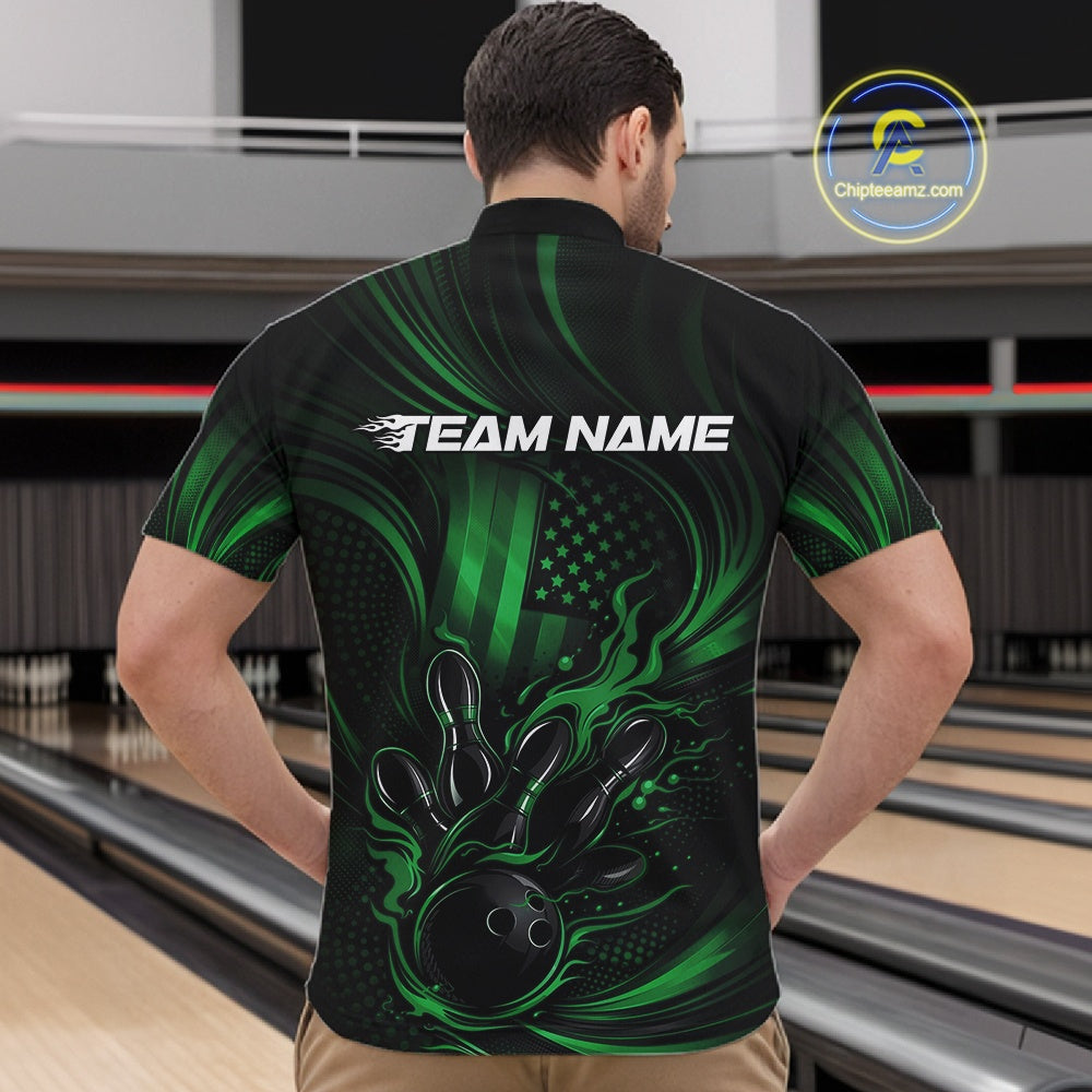 Front view of a male model in a bowling center wearing a black and green quarter-zip shirt featuring flaming bowling ball artwork and patriotic pin graphics.