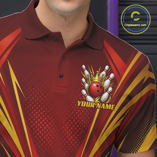 A close-up of a custom short-sleeve polo shirt worn by a male model. The shirt features a dark red base with gold and orange graphic stripes, a bowling pins and ball crown emblem, and the customizable text 'YOUR NAME'.