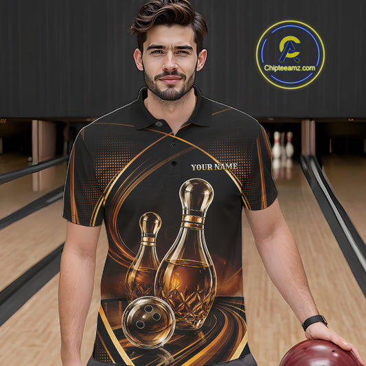 A man in a bowling alley wearing a black short-sleeve polo shirt with a custom bowling pins that resemble wine bottles and ball graphic in gold and brown, holding a bowling ball. 