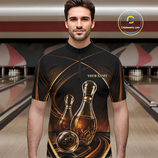 A man wearing a black short-sleeve bowling-themed quarter-zip shirt with a graphic print of bowling pins that resemble wine bottles, bowling balls, and gold swirls, set against a blurred bowling alley background.