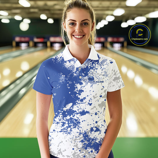 Female model front view at bowling lane wearing white polo shirt with blue and white splatter pattern, casual sporty bowling center environment
