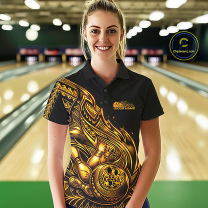 Female model wearing a black and gold bowling polo shirt at the lane with Polynesian-inspired flame bowling motifs.