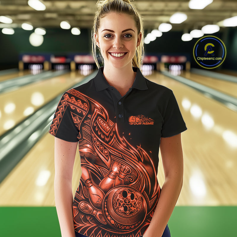 Female model wearing a black and orange bowling polo shirt at the bowling lane with Polynesian-style tribal flame graphics.