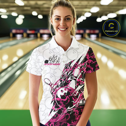 Female model wearing a white bowling polo shirt at the lane with pink camo-inspired bowling graphics and subtle bowling ball patterns.