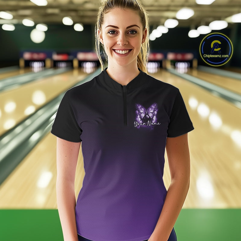 Female model wearing a purple bowling quarter-zip shirt at a bowling lane with luminous butterfly artwork, a bowling ball, and fallen pins.