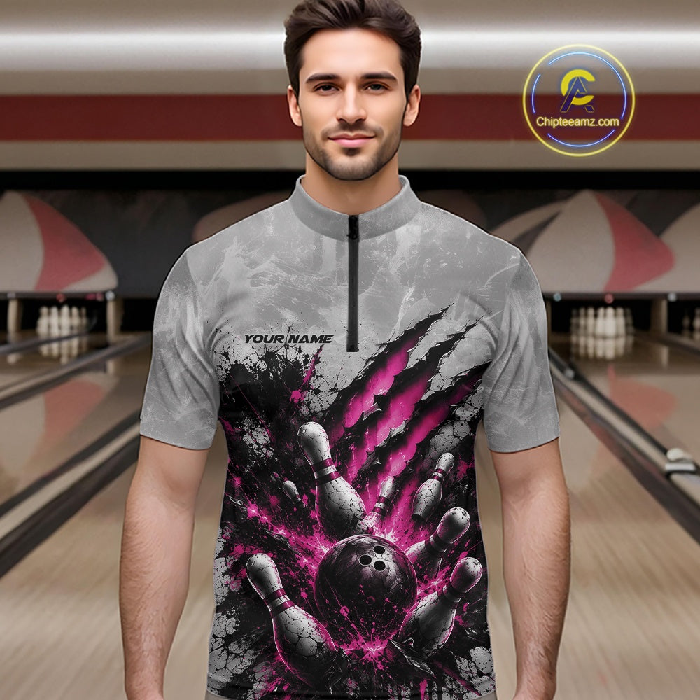 Front view of a male model wearing a gray bowling quarter zip shirt featuring a dramatic pink bowling ball and pins graphic with claw-mark artwork in a bowling lane.