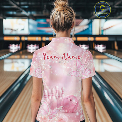 Back view of a female model at a bowling lane wearing a polo shirt featuring pink glitter butterflies, roses, bowling pins, and bowling ball artwork.