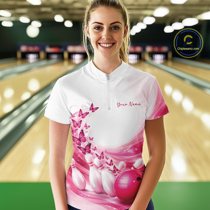 Front view of a female model wearing a white and pink bowling quarter zip with butterfly accents and bowling graphics at the bowling lane.