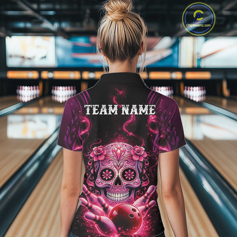 Back view of a female model in a bowling alley wearing a black and pink quarter-zip shirt showcasing a floral sugar skull, bowling ball, and bowling pins artwork.