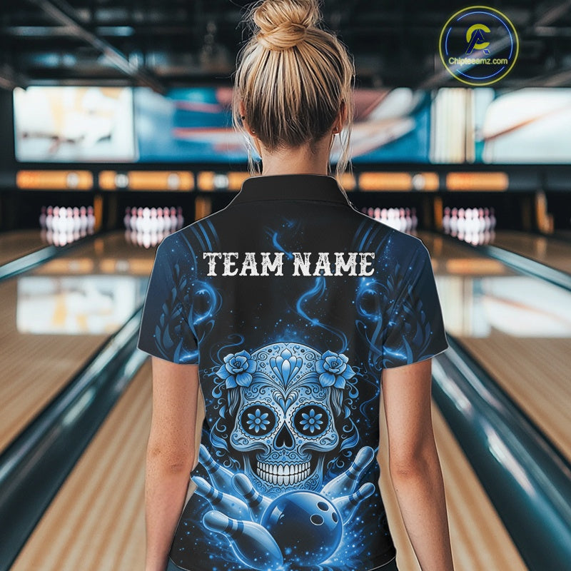 Back view of a female model in a bowling alley wearing a black and blue quarter-zip shirt showcasing a sugar skull, bowling ball, and pin design.