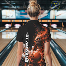 Load image into Gallery viewer, Back view of a female model in a bowling alley wearing a black bowling polo shirt featuring an orange fiery skull with lightning striking a bowling ball and pins and a custom name.

