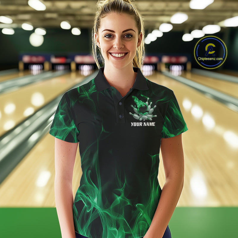 Female model at a bowling lane wearing a black and green bowling polo shirt with scattered bowling pins and fiery bowling action graphics.
