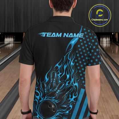 Back view of a male model in a bowling alley wearing a black polo shirt featuring a blue flaming bowling ball knocking down pins.