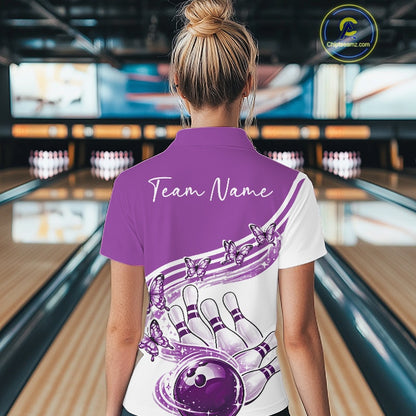 Back view of a female model wearing a white and purple bowling polo with butterfly graphics and bowling artwork inside a bowling alley