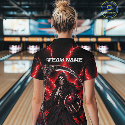 A woman viewed from behind wearing a black short-sleeve bowling shirt with a large grim reaper graphic, red lightning, and the text 'TEAM NAME' on the back. The background shows blurred bowling lanes in a bowling alley.
