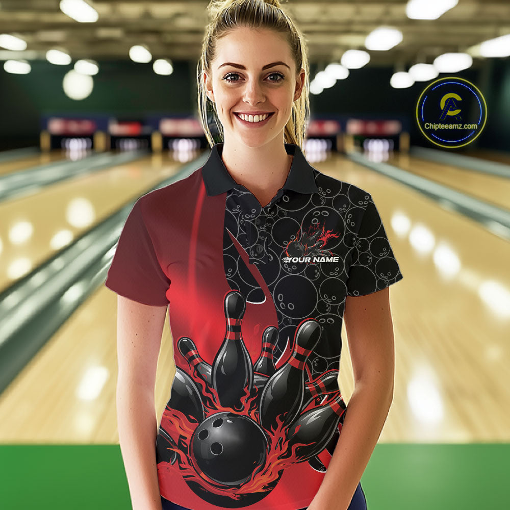 Front view of a female model in a bowling lane wearing a black and red polo shirt with flaming black bowling ball striking pins and bold athletic visuals.