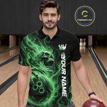 Load image into Gallery viewer, Male model wearing a black bowling polo shirt in a bowling alley featuring a skull clutching a bowling ball surrounded by swirling green energy flames